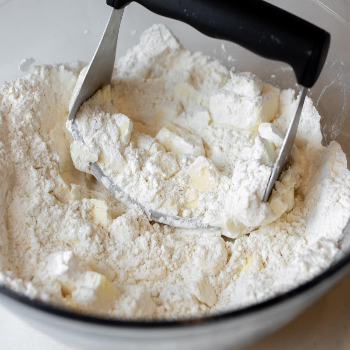 Butter being cut into flour in a bowl.